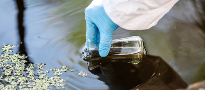 Gloved Hand Using Glass Bottle for Water Testing