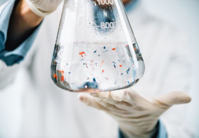 Professional holding water sample with microplastics