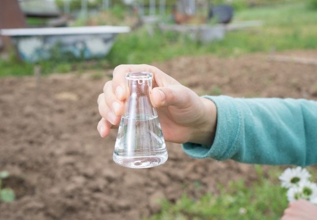 Person holding glass vile with water in it