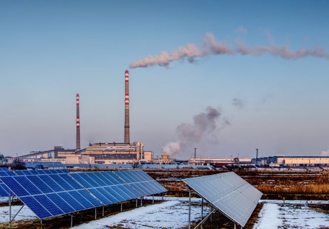 Solar panels with coal plant in the background